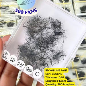 May include: A clear plastic tray containing black 5D volume eyelash extension fans. The tray features printed text including 500 FANS, 5D, 0.07, 12mm, and C. A yellow label lists specifications: 5D VOLUME FANS, Curl: C /CC/ D, Thickness: 0.07, Lengths: 8-17mm, Quantity: 500 fans/box, Material: PBT from Korea, Wholesale, OEM, ODM available.