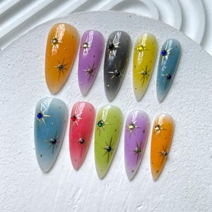 Puede incluir: Diez u&ntilde;as postizas de diferentes colores con un dise&ntilde;o de estrella y pedrer&iacute;a. Las u&ntilde;as est&aacute;n en un degradado de color, cada u&ntilde;a es un tono diferente del mismo color.