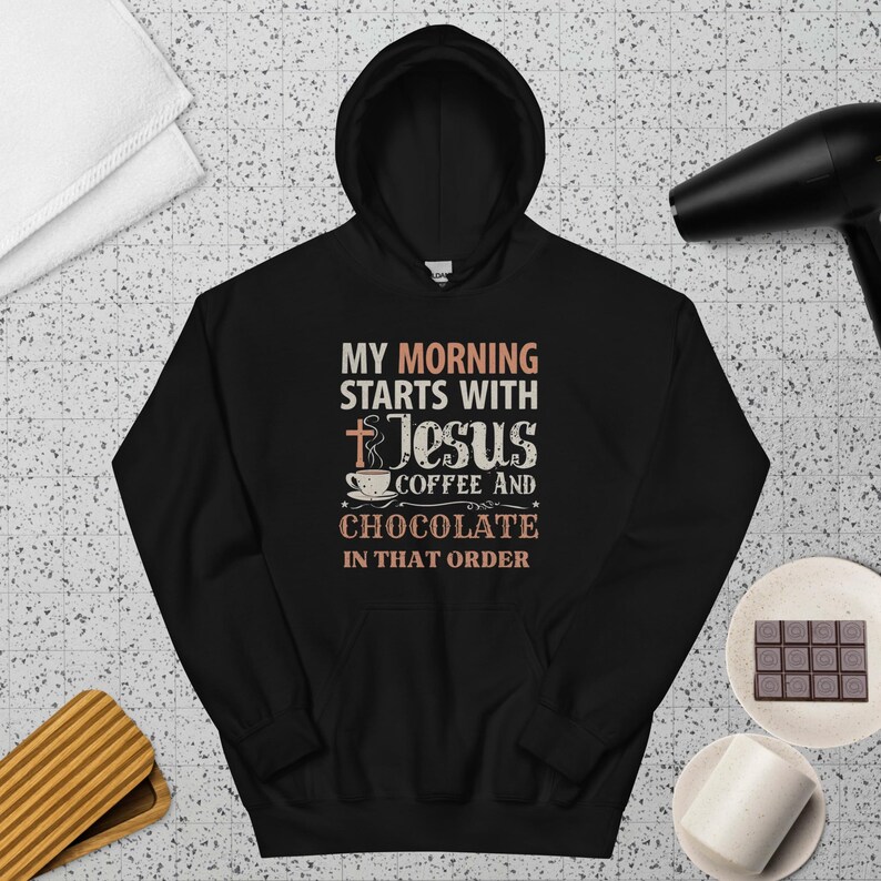 Peut inclure: Sweat &agrave; capuche noir avec l'inscription "MY MORNING STARTS WITH JESUS COFFEE AND CHOCOLATE IN THAT ORDER". Le design comprend une croix, une tasse &agrave; caf&eacute; et des &eacute;toiles.