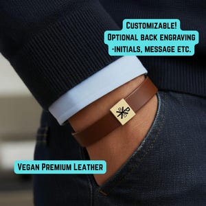 May include: Brown vegan leather bracelet with a gold-colored square clasp. The clasp features a symbol. Text on the image reads: "CUSTOMIZABLE! OPTIONAL BACK ENGRAVING -INITIALS, MESSAGE ETC." and "VEGAN PREMIUM LEATHER."
