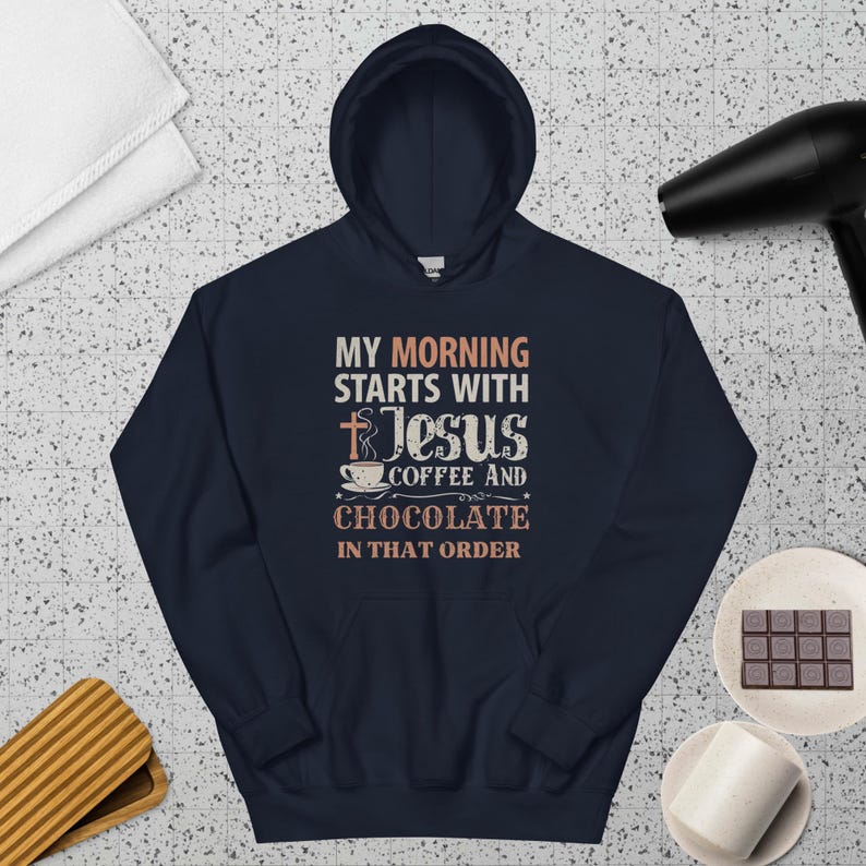 Peut inclure: Un sweat &agrave; capuche bleu marine avec l'inscription "MY MORNING STARTS WITH Jesus COFFEE AND CHOCOLATE IN THAT ORDER" en cr&egrave;me. Le design comprend une croix, une tasse &agrave; caf&eacute; et des &eacute;toiles.