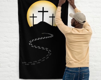 May include: A black fabric banner with a yellow moon and three crosses on a hill. Footprints lead away from the hill. The banner is being hung on a white brick wall.