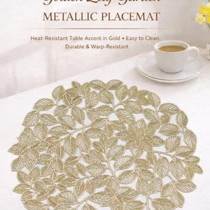 May include: A gold metallic placemat with a leaf design. The round placemat has the text "Golden Leaf Garden METALLIC PLACEMAT". A white teacup and saucer are in the background.