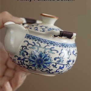 May include: A white and blue floral patterned teapot with a built-in filter and extra-large spout. The teapot has a finely polished bottom and a brown handle. The text on the image says "A Sleek and Elegant Design".