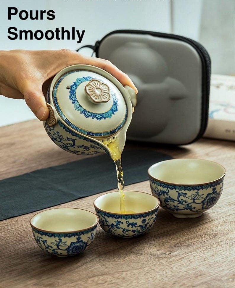 Puede incluir: Un juego de t&eacute; de cer&aacute;mica con una tetera y dos tazas. La tetera es blanca con dise&ntilde;os florales azules y un asa marr&oacute;n. El t&eacute; se vierte en las tazas. El texto "Pours Smoothly" est&aacute; en la esquina superior izquierda.
