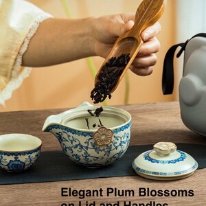Puede incluir: Un juego de t&eacute; con un dise&ntilde;o floral azul y blanco. El juego incluye una taza peque&ntilde;a, una tetera con tapa y una cuchara de madera. El texto "Elegant Plum Blossoms on Lid and Handles" es visible.