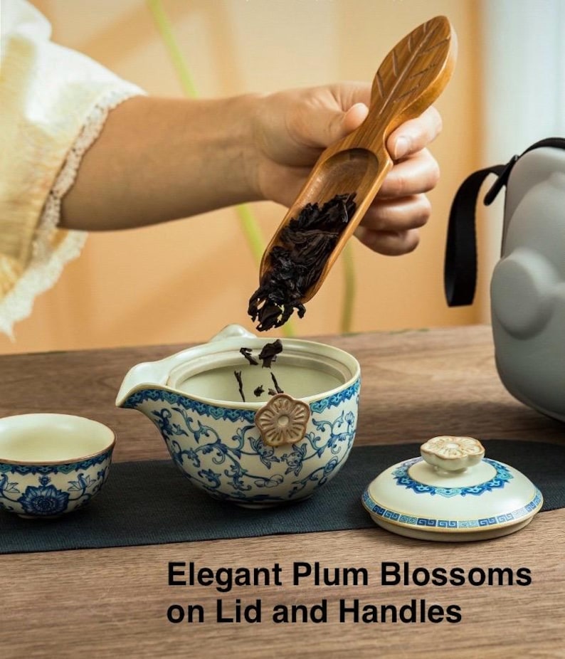 Puede incluir: Un juego de t&eacute; con un dise&ntilde;o floral azul y blanco. El juego incluye una taza peque&ntilde;a, una tetera con tapa y una cuchara de madera. El texto "Elegant Plum Blossoms on Lid and Handles" es visible.