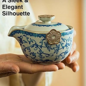 Puede incluir: Una tetera de cer&aacute;mica con un dise&ntilde;o floral azul y blanco, sostenida en una mano. La tetera tiene un pico, una tapa y un asa en forma de flor. El texto en la imagen dice: "A Sleek & Elegant Silhouette."