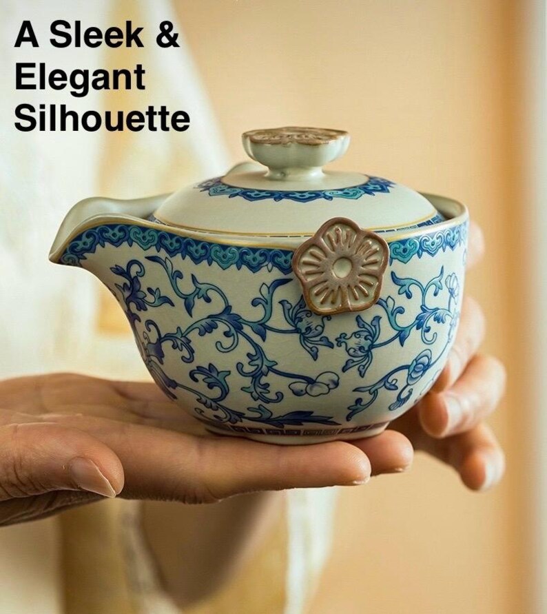 Puede incluir: Una tetera de cer&aacute;mica con un dise&ntilde;o floral azul y blanco, sostenida en una mano. La tetera tiene un pico, una tapa y un asa en forma de flor. El texto en la imagen dice: "A Sleek & Elegant Silhouette."