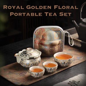 May include: A Royal Golden Floral Portable Tea Set. The set includes a teapot, three teacups, and a carrying case. The teapot and cups are white with gold and blue floral designs. The tea is amber-coloured.