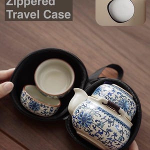 May include: A black zippered travel case containing a small tea set. The tea set includes a teapot and two cups, all decorated with blue floral patterns. The text "Protective Zippered Travel Case" is visible.