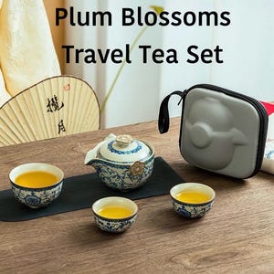 May include: A travel tea set with the text "Plum Blossoms Travel Tea Set". The set includes a teapot, three teacups, and a carrying case. The teapot and cups have a blue and white floral design. The tea is a golden yellow color.