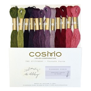 May include: A set of twelve Cosmo embroidery thread skeins in a gradient of green, black, purple, and red shades. Each skein features a gold paper band with the text Cosmo. The packaging includes the text The Stitchery and Blackberry Picking.