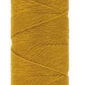 May include: A spool of yellow WonderFil thread. The thread is tightly wound around a white spool, with the brand name "WonderFil" printed on the top and "EN46" on the bottom. The thread has a textured appearance.