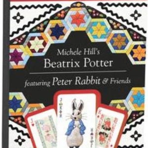 May include: A black playing card box featuring "Michele Hill's Beatrix Potter" with Peter Rabbit & Friends. The box has a colorful geometric design and shows three playing cards with Peter Rabbit illustrations.