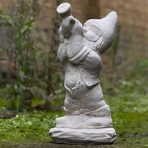 Puede incluir: Una estatua de gnomo de jardín de hormigón blanco tocando la trompeta. El gnomo lleva un sombrero y tiene barba. La estatua está sobre una base con textura rugosa.