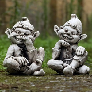May include: Two gray stone garden gnomes with mischievous smiles, one is covering its mouth with its hand, the other is holding its chin with its hand.