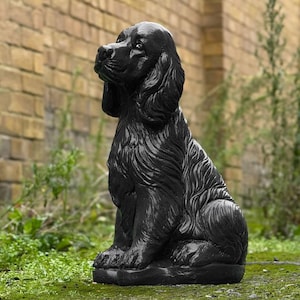 Könnte beinhalten: Schwarze, detaillierte Keramikskulptur eines sitzenden Hundes. Der Hund schaut nach oben und hat ein langes, fließendes Fell.