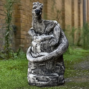 Puede incluir: Una escultura de piedra gris de un dragón enroscado alrededor de una roca. El dragón tiene un cuerpo texturizado y escamoso y una cara detallada.