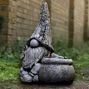 以下が含まれることがあります： 長いひげと質感のある帽子を持つ灰色の庭のノーム像。ノームは大きくて丸いポットを持っています。像は石でできており、屋外での使用に適しています。