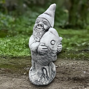 May include: A gray garden gnome statue holding a large fish. The gnome has a pointed hat, a long beard, and is smiling. The fish has a large eye and scales. The statue is made of a stone-like material and is outdoors.