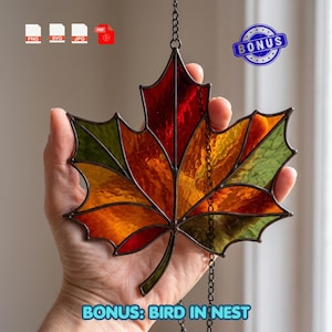 May include: A stained glass maple leaf suncatcher featuring textured panels in shades of red, orange, and green, held by a dark metal frame. The piece includes a hanging chain and is accompanied by digital file icons and a bonus label.