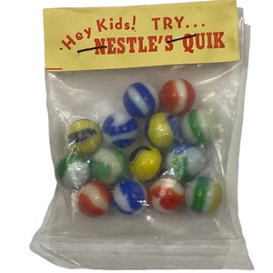May include: A plastic bag filled with colourful marbles. The bag has a yellow label with the text "Hey Kids! TRY... NESTLE'S QUIK."