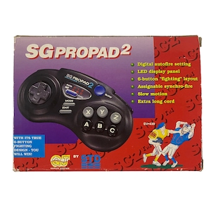 May include: A black Sega Genesis controller with a red and blue label that reads "SG Propad 2". The controller is on a red box with white text that reads "SG Propad 2" and lists features like "Digital autofire setting" and "Extra long cord".
