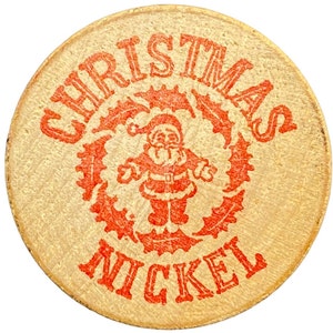 Puede incluir: Una ficha redonda de madera con las palabras "Christmas Nickel" impresas en rojo. En el centro hay una ilustración roja de Papá Noel rodeado de hojas de acebo.