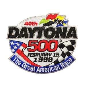 May include: Embroidered patch commemorating the 40th Daytona 500 race held on February 15, 1998. Features the words "DAYTONA 500" in black, red, and white, with a checkered flag and American flag design. The text "The Great American Race" is also included.