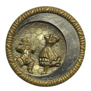 Peut inclure: Un bouton rond de couleur dorée avec un motif en relief d'un couple dansant. L'homme est habillé en bouffon et la femme porte une longue robe. Le bouton a un fond texturé en forme de nid d'abeille.
