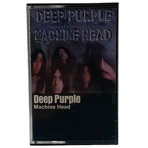 May include: A black cassette tape with a picture of the band Deep Purple on the front. The title "Deep Purple Machine Head" is printed in white on the front of the cassette tape.