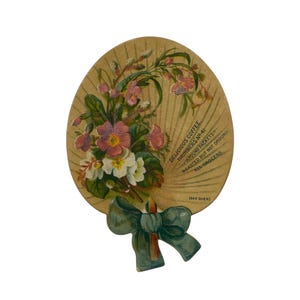 May include: Vintage oval-shaped advertisement for coffee. The design features a bouquet of pink and white flowers with green leaves, tied with a teal bow. Text reads "Delicious Coffee" and other details about the product.