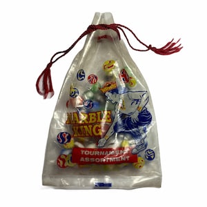 May include: A clear plastic bag with a red drawstring filled with colourful marbles. The bag has a printed image of a boy playing marbles with the text "Marble King Tournament Assortment".