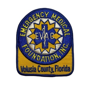 May include: Embroidered patch with the text "Emergency Medical Foundation, Inc." in a circular design. The patch has a blue border with yellow text and a central emblem. The text "Volusia County, Florida" is at the bottom.