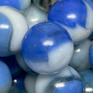 May include: A collection of blue and white glass marbles. The marbles have a swirling pattern of blue and white.