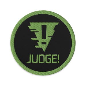 May include: Green and black embroidered patch with a green exclamation mark inside a green triangle and the text "JUDGE!" below.