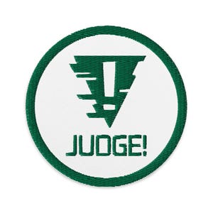 May include: An embroidered patch featuring a green triangle with a white exclamation mark and the text "JUDGE!" underneath, all on a white background.