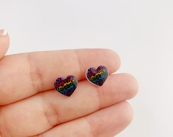 May include: A pair of heart-shaped stud earrings featuring a vibrant rainbow-colored leopard print pattern. The design incorporates a spectrum of colors including red, orange, yellow, green, blue, and purple, arranged in a spotted animal print motif.