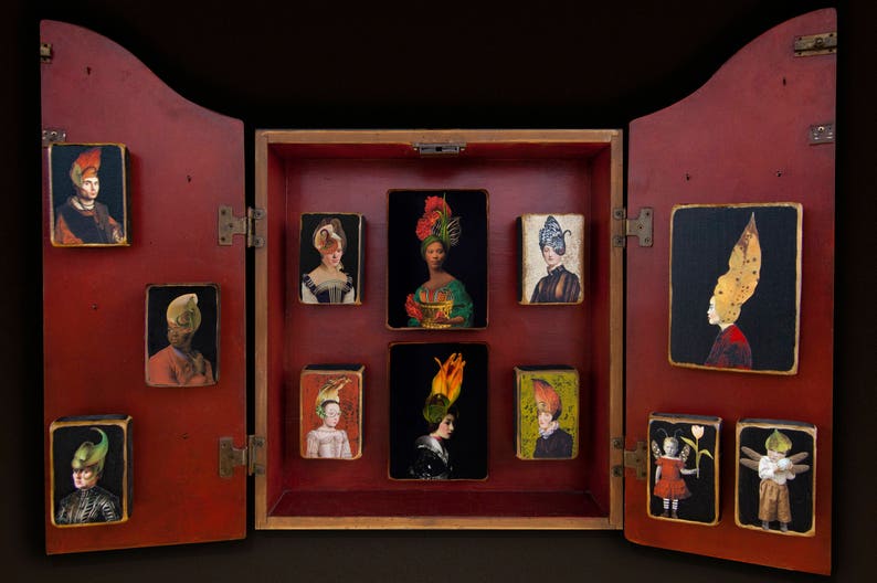 May include: A red wooden cabinet with a hinged door, revealing a series of small framed portraits of people wearing elaborate hats. The portraits are arranged in a grid pattern and are set against a gold background.
