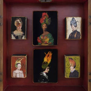 May include: A wooden box containing six framed images of women wearing elaborate headdresses. Each image has a different background colour and features a unique headdress design.