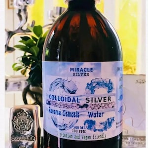 May include: A brown glass bottle with a white label that reads "Miracle Silver Colloidal Silver Reverse Osmosis Water 500 ml 100 ppm Vegetarian and Vegan friendly". The bottle is next to a silver bar that reads "Scottsdale 999 Fine Silver 10 Troy Oz".