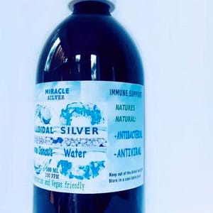 May include: A clear glass bottle with a white cap, containing a dark liquid. The label reads "Miracle Silver Colloidal Silver Osmosis Water 500 ml 100 ppm" and "Immune Support Natures Natural: -Antibacterial -Antiviral Keep out of the direct sunlight Store in a cool dark place".