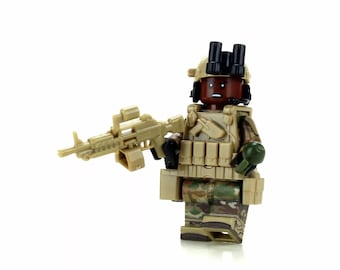 May include: A tan and green camouflage military action figure with a black helmet and a tan machine gun. The figure is holding a green grenade in its left hand.
