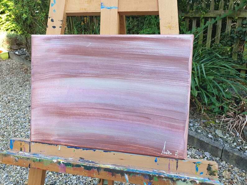 May include: Abstract painting on canvas with horizontal brushstrokes in shades of pink, white, and brown. The painting is on an easel.