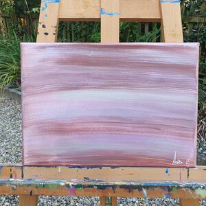 May include: Abstract painting on canvas with horizontal brushstrokes in shades of pink, purple, and white. The painting is signed "Andie F" in the bottom right corner.