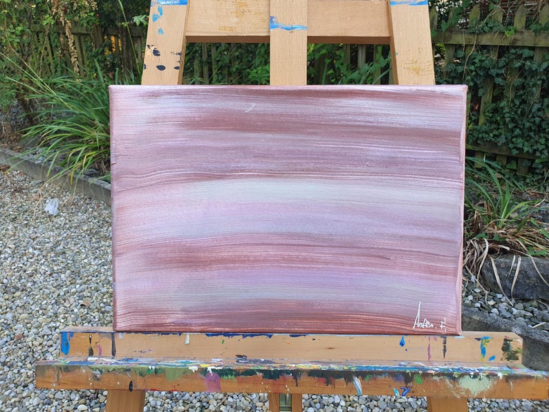 May include: Abstract painting on canvas with horizontal brushstrokes in shades of pink, purple, and white. The painting is signed "Andie F" in the bottom right corner.