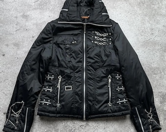 May include: Black puffer jacket with silver hardware, including chains, studs, and zippers. The jacket has a high collar and a zipper closure.