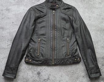 以下が含まれることがあります： 黒い革のジャケット。フロントはジッパー開閉、ジッパー付きポケットが2つ、スタンドカラー。ジャケットはフィットしたシルエットで、装飾的なステッチのディテールが特徴です。袖口はスナップ留めです。