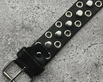 May include: Black leather belt with silver-tone metal studs and eyelets. The belt features a silver buckle and a matching belt loop. The design is a classic punk or rock-and-roll style.